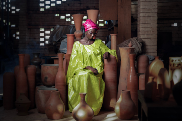 Young woman in a green dress in front of pottery