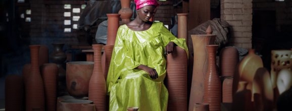 Young woman in a green dress in front of pottery