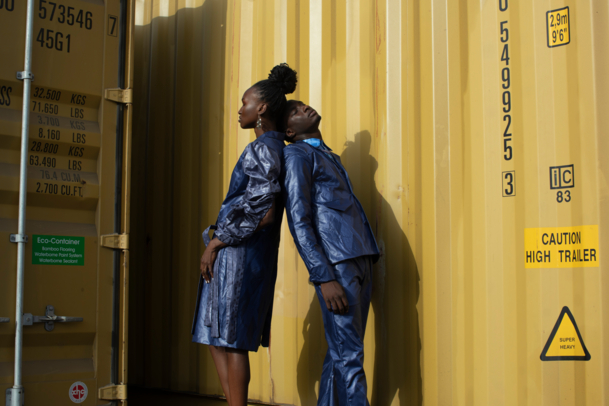 Two people posing in front of a yellow container