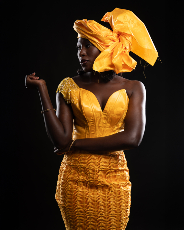 Woman in a fitted yellow dress with big headtie