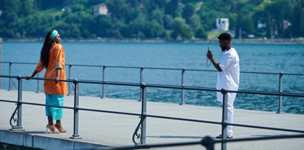 Un homme photographie une femme sur un ponton au bord de l'eau