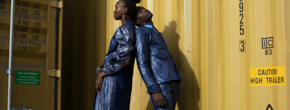 Two people posing in front of a yellow container